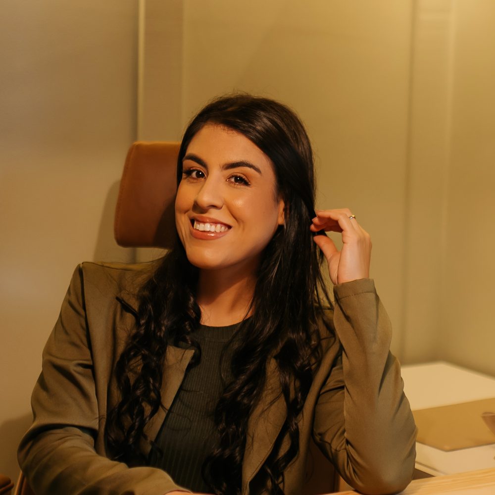 Aline sentada a uma mesa de trabalho